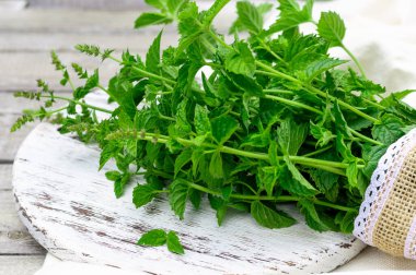 Taze yapraklar, nane kökleri beyaz ahşap bir arka planda yatıyor.