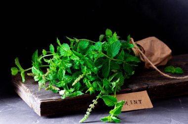 Taze yaprak buketi, nane, nane sapları, ahşap bir arka planda yatıyor, sade anahtar.