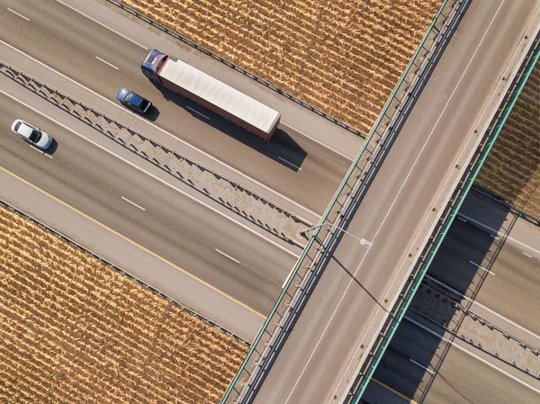Dump truck carrying goods on the highway. Blue truck driving on asphalt road along the yellow fields. seen from the air. Aerial view landscape. drone photography. cargo delivery — Stock Photo, Image