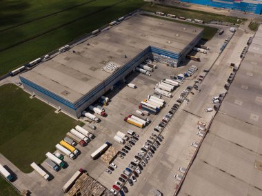 Depolu büyük lojistik parkının havadan görünüşü, yükleme malları için rampalarda bekleyen bir sürü yarı karavan dolu merkez..