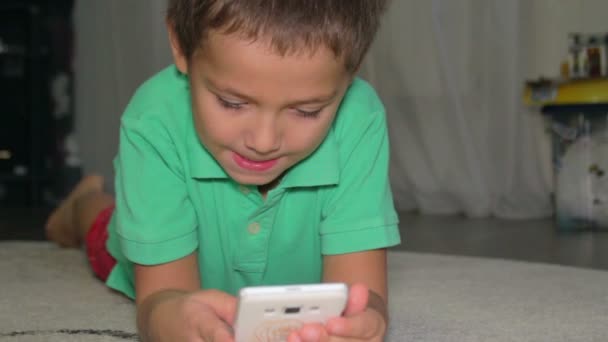 Caucasiano menino joga jogo no telefone . — Vídeo de Stock