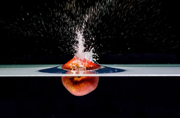 Siyah arka plan üzerine izole suya sıçramasına Kırmızı elma