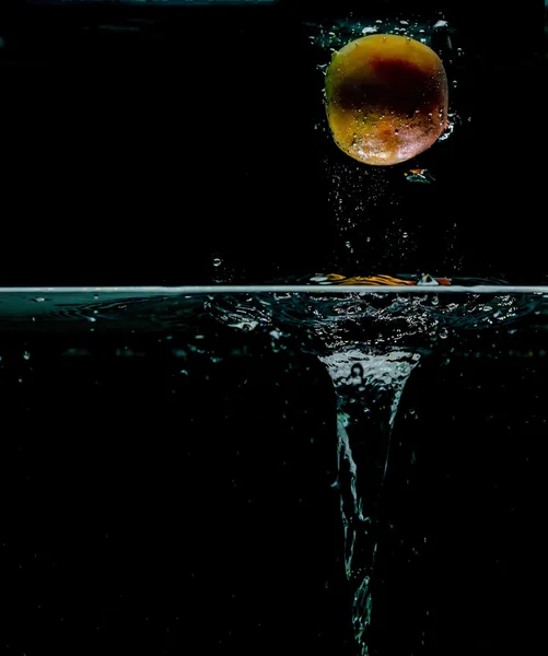 Abrikoos spatten in water, geïsoleerd op zwarte achtergrond — Stockfoto