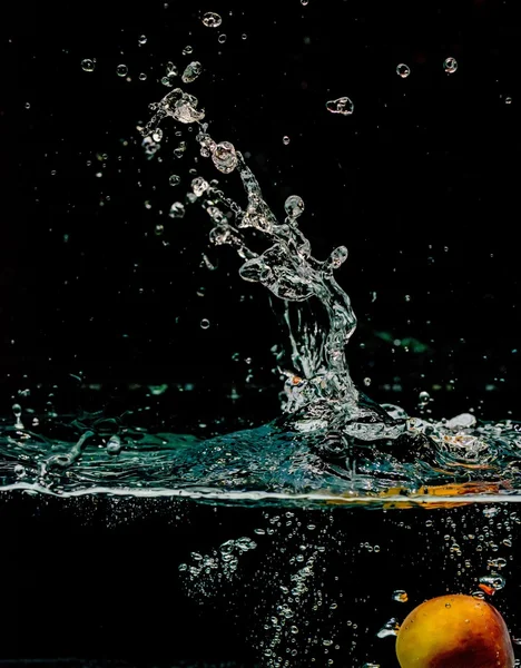 Абрикосовые брызги в воду, изолированные на черном фоне — стоковое фото
