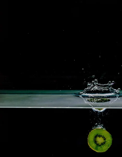 Плоды киви в воду, изолированные на черном фоне — стоковое фото