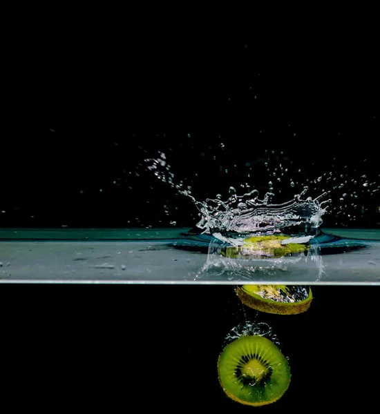 Fruto kiwi en el agua, aislado sobre fondo negro —  Fotos de Stock