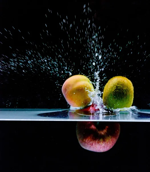 Fruta mezclada salpicando en el agua — Foto de Stock