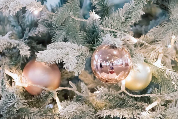 Kugeln und Girlanden hängen an Tannenzweigen vor festlicher Kulisse. Goldene Kugeln auf Fichte. Weihnachtlicher Hintergrund. Frohe Weihnachten und einen guten Rutsch ins neue Jahr. — Stockfoto