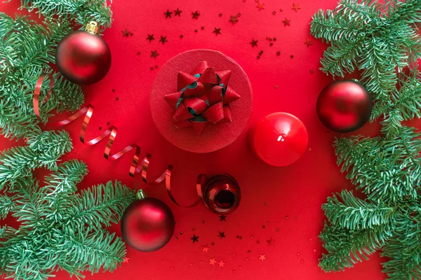 Weihnachtskomposition aus Weihnachtsgeschenk, Kerze, Tannenzweigen, Kugeln auf roter Oberfläche. Frohe Weihnachten und ein gutes neues Jahr. Flache Lage — Stockfoto