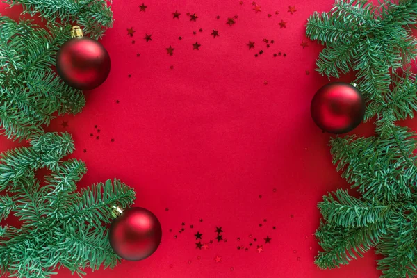 Fond de Noël rouge décoré avec des branches d'arbre, des paillettes et des boules, des décorations festives de vacances d'hiver. Joyeux Noël et heureux concept du Nouvel An 2021. Pose plate, vue du dessus, espace de copie — Photo