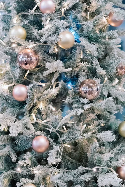 Kugeln und Girlanden hängen an Tannenzweigen vor festlicher Kulisse. Goldene Kugeln auf Fichte. Weihnachtlicher Hintergrund. Frohe Weihnachten und einen guten Rutsch ins neue Jahr. — Stockfoto