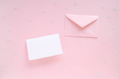 Boş Noel kartı ve pembe zarf, pembe yüzey üzerinde Noel süslemeleri, üst manzara. Tatil hipster çalışma alanı maketi, kopyalama alanı.