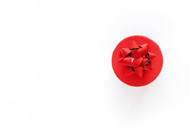 Beyaz yüzeyinde dekoratif fiyonk olan kırmızı hediye kutusu, üst manzara, kopyalama alanı. Tatil konsepti, yeni yıl ya da Noel, doğum günü ya da Sevgililer Günü hediye paketi