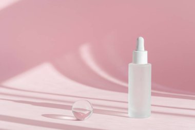 Kolajenle serum yağı ve beyaz şeffaf şişede peptit ve gölgeli pembe dekor arkaplanı üzerine damlatıcı. Cilt bakımı, tıbbi cilt bakımı, makyaj ürünleri.