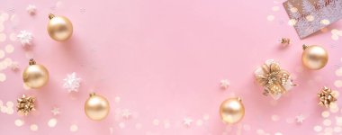 Noel kompozisyonu. Hediye, takılar, tebrik kartı, pastel pembe yüzeyde altın süslemeler. Noel, kış, yeni yıl konsepti. Düz konum, üst görünüm, kopyalama alanı, yukarıda, pankart