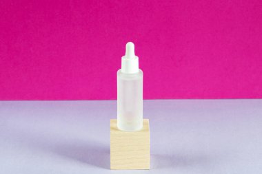 Hiyalüronik asit yağ tentürü, kaidesel vitrinde. Kolajen ve peptidli serum, tahta küp podyumda. Güzellik ürünü sunumu. Ürün reklamı, eko kozmetik konsepti