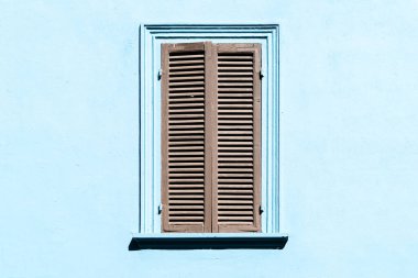 Penceredeki gri panjurlar mavi renkli bir duvara karşı. İtalyan ya da Yunan köyünde penceresi kapalı eski bir dış mekan.