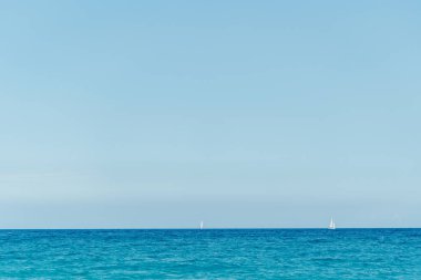 Ufuk ve mavi gökyüzü ile okyanusun ya da gölün sakin yüzeyi.