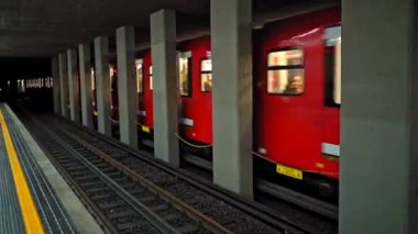 İçinde metro istasyonundan geçen insanlar olan kırmızı metro treni. Yeraltı treni platformdan kalkıyor. Avrupa modern toplu taşımacılık. 