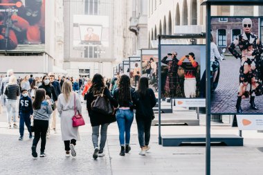 Milan, İtalya - 27 Eylül 2020. Milano şehir merkezindeki maskeli insanlar güneş pilleri kullanarak gezip, modern moda fotoğrafçılık sokak sergisine bakıyorlar. Yeni normal covid