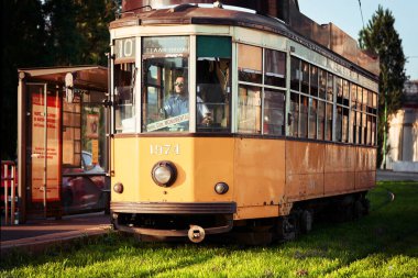 Sarı tramvay, tramvay durağının yanında duruyor. Güneşli bir günde Milano şehir merkezinde ünlü bir klasik tramvay. 26 Mayıs 2020 - Milan, İtalya
