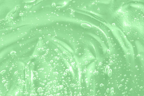 Hyaluronic acid clear serum sample. Aloe vera cosmetic gel texture with bubbles background. Liquid green oil smudge.