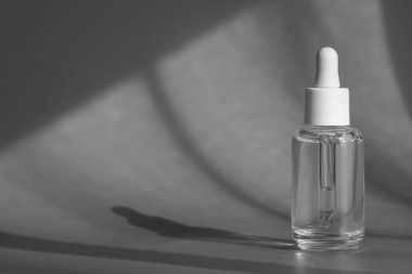 Pipetli cam kozmetik şişesi, kolajen ve peptid içeren yaşlanma önleyici serum gri arka planda gölgeli ürün ambalajı, kozmetik modelleme, cilt konsepti. Paketleme