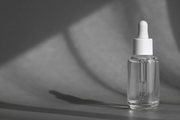 Glass cosmetic bottle with pipette, anti aging serum with collagen and peptides product packaging with shadows from sun on grey background, cosmetic mockup, skincare concept. Packaging