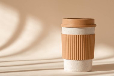 Yeniden kullanılabilir fincan, geri dönüşümlü seyahat edilebilir plastik kahve kupası. Doğal gölge bej arka planda silikon tutacağı olan sürdürülebilir bambu çevre dostu bardak.. 