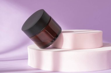 Kahverengi şişedeki boş lüks losyon kavanozu vitrinde duruyordu. Organik yüz kremi kozmetik podyumda, düşük açılı görünümde, boşluğu kopyala