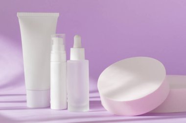 Cilt bakımı kozmetik şişeleri leylak üzerinde maket yapıyor. Krema kavanozu tüpü, serum cam şablonu, arka planda gölgeli losyon kutusu, ön görüş. Marka spa paketleme maketi.