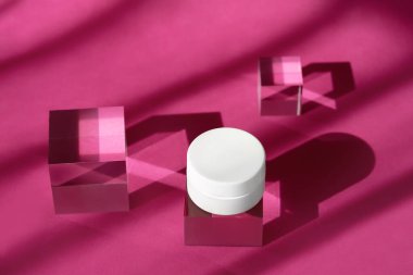 Cam küp kürsünün üstünde duran bir kavanoz organik krema modeli. Vücut kremi boş kozmetik şişesi gölgeler ve yansımalarla şeffaf katı bloklar oluşturur..