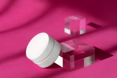 Vücut kremi boş kozmetik şişesi gölgeler ve yansımalarla şeffaf katı bloklar oluşturur. Cam küp kürsünün üstünde duran bir kavanoz organik krema modeli..