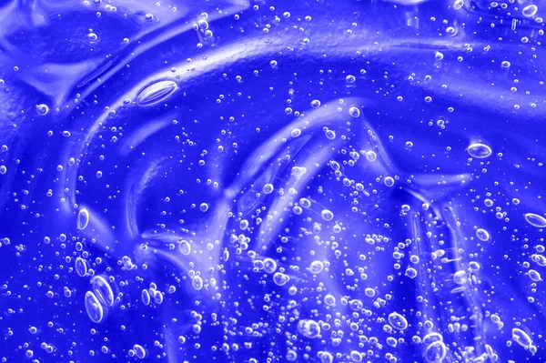 Hyaluronsyra klart serumprov. Flytande antibakteriell desinficera smutskastning. Kosmetisk blå gel konsistens med bubblor. Hudvård återfuktande produktbakgrund. Slagpåse för saneringsmedel. — Stockfoto