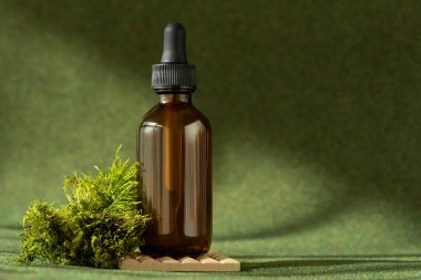 Yeşil arka planda pipeti olan kozmetik serumu şişesi.