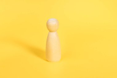 Sarı arka planda tek başına duran tahtadan bir kadın heykeli. Kendine güvenen bağımsız kişi, akıl hocası, koç, lider konsepti.