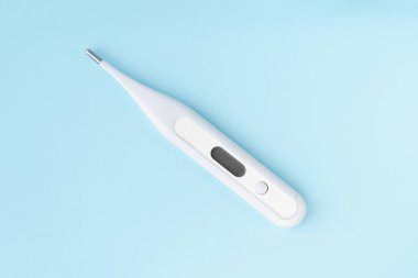 Mavi arka planda elektronik vücut termometresi. Dijital ekranlı modern termometre, tanı aracı