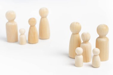 Beyaz arka plandaki ahşap heykelciklerden yapılmış aile üyeleri. İzolasyon, aileler arasındaki sosyal uzaklık