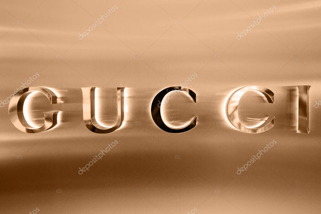 Gucci boutique exterior sign, italian luxury brand of fashion goods and leather goods. Illuminated Gucci logo of apparel store showcase. Fashion district in Milan. Milan, Italy - 15.12.2020