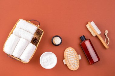Spa seti, havlular, masaj fırçası, kahverengi yüzeyde vücut kremi. Eko sıfır atık kavramı. Spa masajı ve vücut tedavisini gevşet
