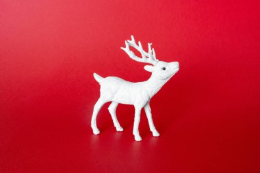 Kırmızı arka planda beyaz rengeyiği. Geyik oyuncağı. Noel minimal konsepti, ön görünüm