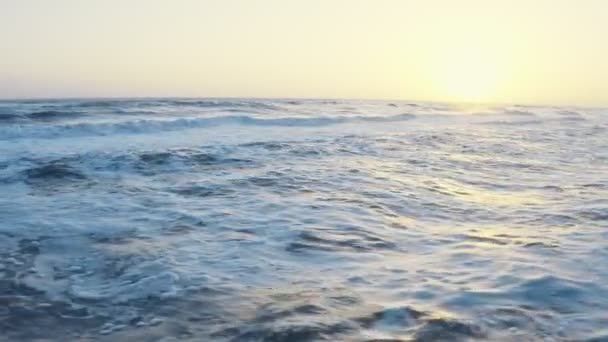 Vliegen over de zee tijdens het gouden uur. Luchtdrone zicht op golven schuimend en spetterend in de zee. Zonsondergang golvend zeegezicht. Zonsondergang boven oceaangolven. — Stockvideo