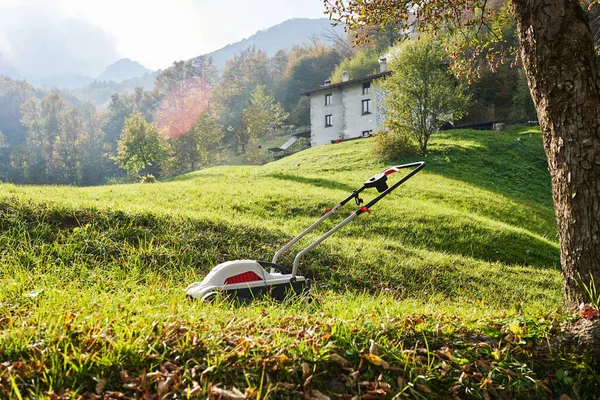 Çim biçme makinesi, yeşil çimlerde çim biçme makinesi İtalyan dağlarının önünde güneşli bir sonbahar günü. Valsassina