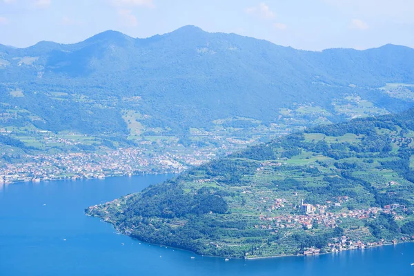 Vista aérea del lago Iseo, montañas boscosas, varios pueblos dispersos a lo largo de las laderas de las montañas y a lo largo de la costa. Lago Iseo en la provincia de Brescia, Lombardía, Italia — Foto de Stock