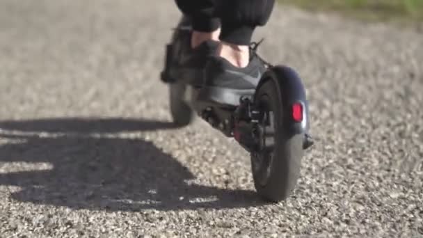 Feminino montando scooter elétrico pontapé ou e-scooter na cidade ou parque de perto. Conceito de transporte urbano elétrico. Conceito de Comutador. Milão, Itália - 4 de abril de 2021. — Vídeo de Stock