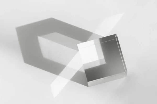 Cube transparent en verre avec réflexion solaire, support géométrique pour cosmétique, lumière et ombre sur blanc. Bloc acrylique, podium pour la présentation des produits — Photo