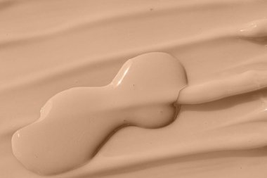 Kozmetik tonal nemlendirici, pansiyon krem numunesi. Bej rengi çıplak sıvı temel dokusu, kapatıcı leke damlası. Makyaj malzemesi, krem desenli arka plan.