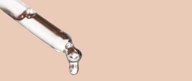 Kozmetik düşürücü, düşüş damlası. Temel yağ damlası olan kozmetik pipeti yakın plan, bej arka planda peptit içeren serum. Kişisel bakım konsepti. Güzellik cilt bakım ürünü.