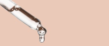 Cosmetics dropper, falling drop close up. Closeup of cosmetic pipette with essential oil dropping, serum with peptides on beige background. Self care concept. Beauty skin care product. clipart