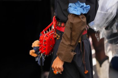 Paris, Fransa - 4 Ekim 2025: Kadınlar kırmızı Snapper Spike takıyor çivili omuz çantası pelüş oyuncak aksesuar ve renkli yüzükler takıyor, sokak tarzı.